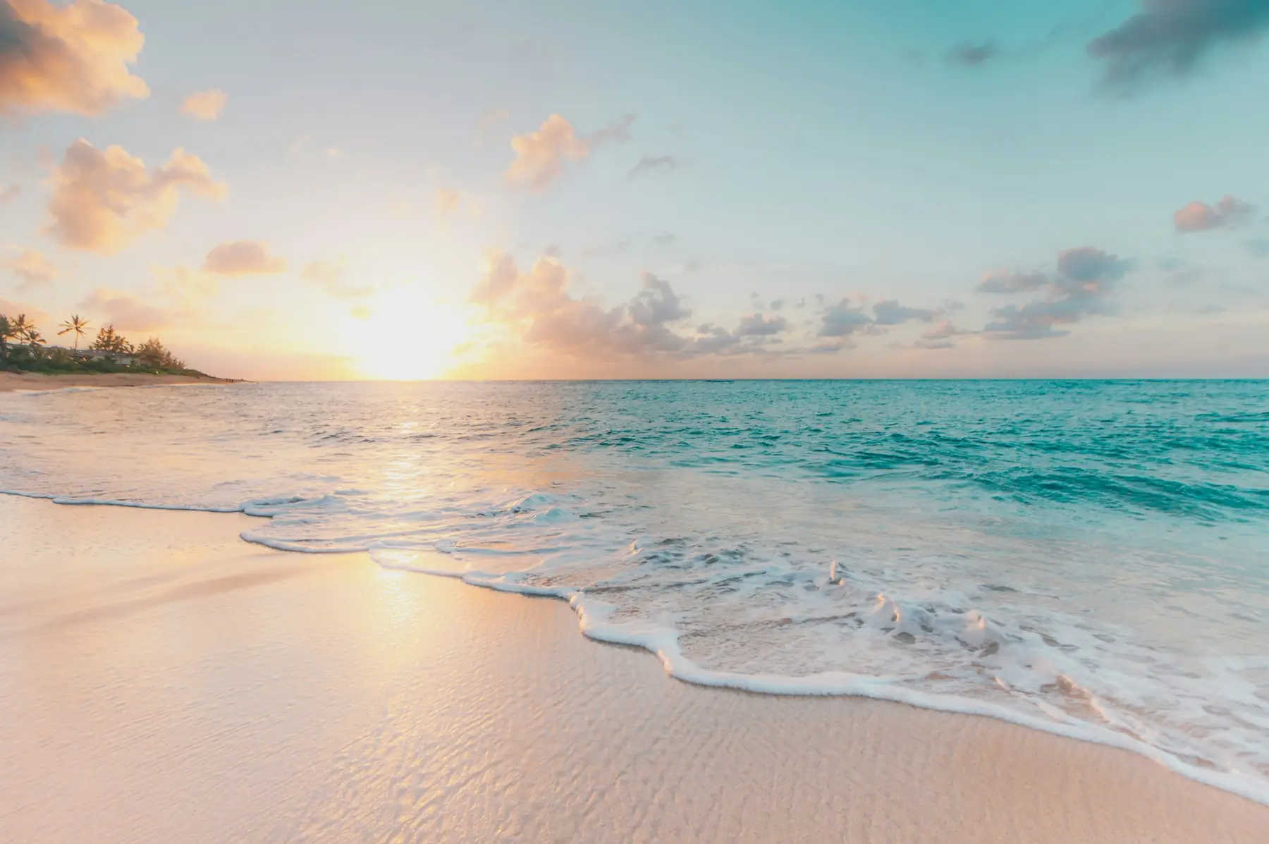 Sonnenuntergang über einem weißen Sandstrand mit türkisem Wasser